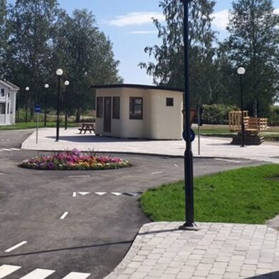 En miniatyr-stad med asfalterad väg, små trähus, lyktstolpar och träd.